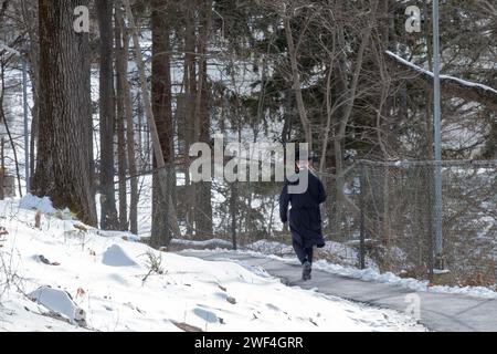 Un juif orthodoxe non identifié vêtu de noir marche sur un chemin dans les bois à New York pendant l'hiver 2024. Banque D'Images