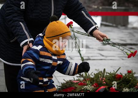 Un enfant dépose des fleurs à la flamme éternelle en mémoire des victimes du siège de Leningrad au cimetière commémoratif de Piskarevskoye à Saint-Pétersbourg. St. Pétersbourg célèbre une date historique importante, 80 ans depuis la libération complète de Leningrad du blocus fasciste. Banque D'Images