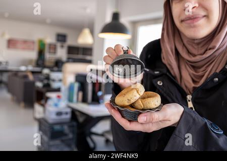 Mains féminines musulmanes tenant des bonbons eid dans le bureau avec le sourire sur son visage Banque D'Images