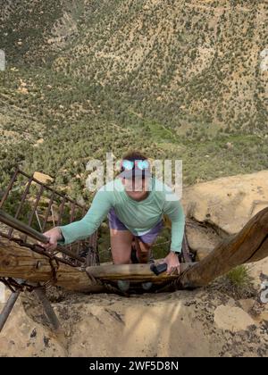 Une femme grimpe à l'échelle lors d'une visite de Balcony House à Mesa Verde Banque D'Images