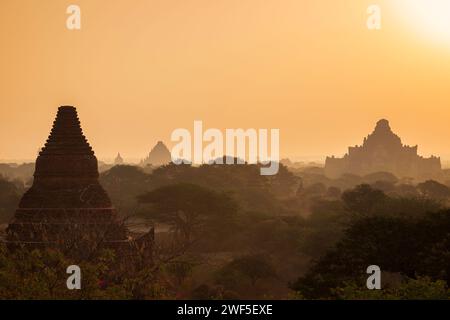 Paysage pittoresque et silhouette de nombreux temples anciens et pagodes à la plaine de Bagan au Myanmar (Birmanie) au lever du soleil. Banque D'Images