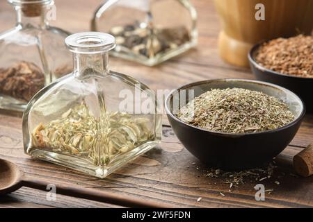 Bouteille d'herbes sèches pour faire l'infusion ou la teinture curative. Bols de plantes médicinales et mortier en bois sur fond. Médecine alternative à base de plantes. Banque D'Images