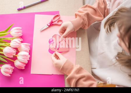 Je t'aime, MOM.MOMS day concept. Mains des enfants tenant une carte de coeur.carte de coeur rose et tulipes roses.fleurs et cartes pour maman. Banque D'Images