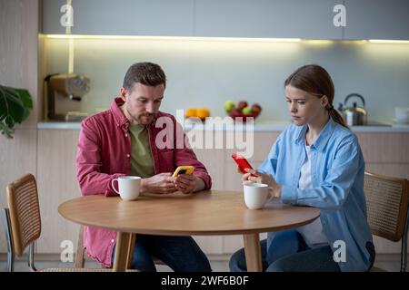 Couple réfléchi accro aux gadgets mobiles surfant sur Internet en silence s'ignorant les uns les autres Banque D'Images