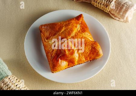 Une composition visuellement étonnante avec une pâte feuilletée parfaitement cuite ornant une assiette blanche immaculée. Banque D'Images