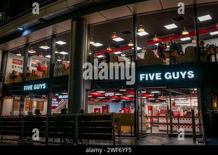 Londres. UK-01.27.2024. Le signe du nom, la façade et l'entrée d'une branche de Five Guys fast-food restaurant dans la rive sud de la Tamise la nuit Banque D'Images