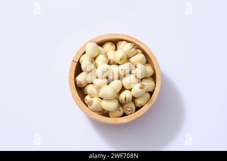 Vue de dessus, couche plate de graines de Lotus (Nelumbo nucifera) placées dans un bol en bois sur fond blanc. Espace de copie. Ingrédients très sains. Banque D'Images