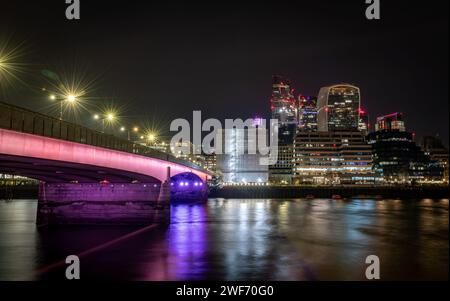 Londres. UK-01.27.2024. Pont de Londres la nuit avec le gratte-ciel dans la City de Londres en arrière-plan et reflets de lumière sur la Tamise. Banque D'Images