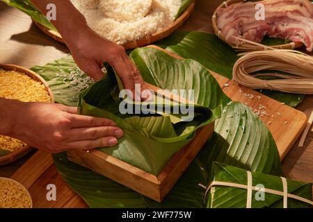 Vue de face du chef faisant le gâteau Chung (gâteau de riz collant) avec le riz de porc et le maïs dans fond de cuisine en bois. Célébration du nouvel an chinois Banque D'Images