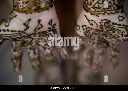 Une femme laisse sécher son tatouage au henné sur ses mains et ses pieds. Banque D'Images