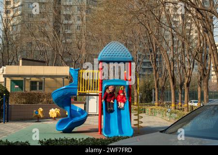 Grand-mère chinoise et son petit-fils jouent sur les installations de divertissement dans un complexe d'appartements à Pékin, en Chine. 29-Jan-2024 Banque D'Images