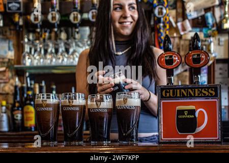 Barmaid dans le pub irlandais The Auld Shillelag tirant Guinness à Stoke Newingtion, Londres, Royaume-Uni Banque D'Images