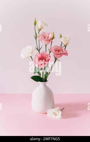 Belles fleurs blanches et roses Eustoma (Lisianthus) dans un vase sur un fond pastel rose. Placer pour le texte. Banque D'Images