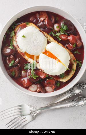 Oeuf poché de Bourgogne à la sauce au vin rouge sur toast oeuf en Meurette gros plan sur l'assiette sur la table. Vue verticale de dessus Banque D'Images