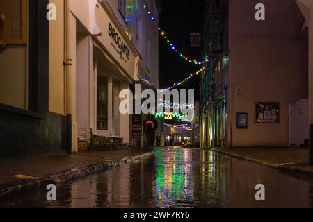 Vue sur Fore Street lors d'une soirée d'hiver humide et calme avec les lumières de Noël suspendues qui se reflètent dans les flaques d'eau sur le sol. Banque D'Images