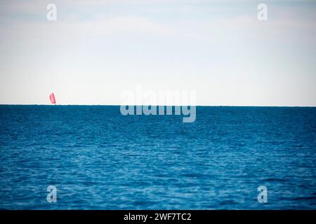 Un voilier lointain morgana effet sur la grande mer bleue, la douce brise soufflant dans les voiles comme les bruits de la ville sont loin. Banque D'Images