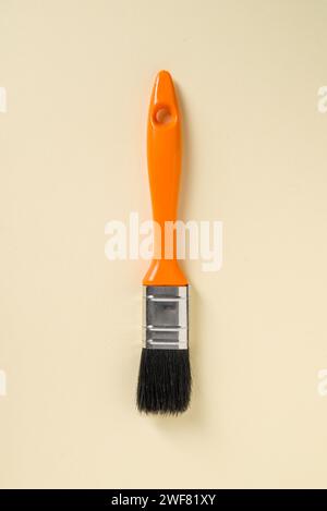 Pinceau de retouche avec poignée orange sur fond jaune Banque D'Images