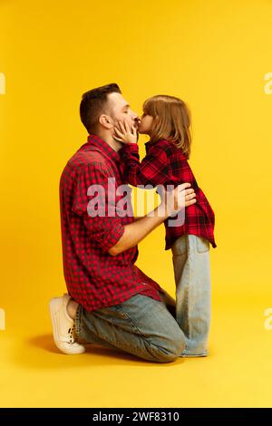 Petit enfant, fille embrassant avec amour son père. Le meilleur père dans le monde et sa belle fille sur fond jaune vif. Concept d'international Banque D'Images