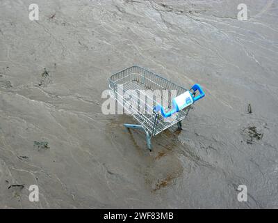 Chariot de supermarché abandonné dans la boue d'une rivière. Banque D'Images