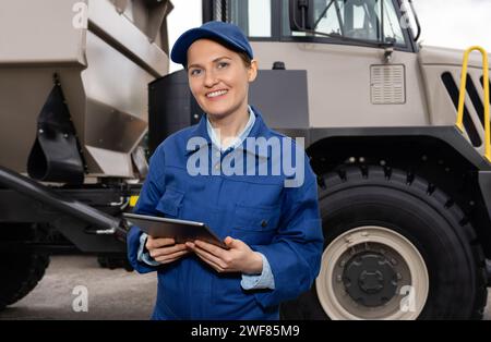 Femme travailleuse avec ordinateur tablette se tient à côté du camion minier. Banque D'Images