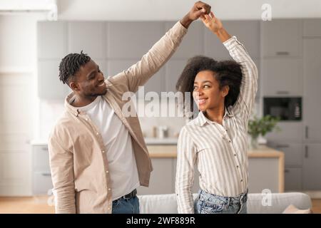 Joyeux jeune couple noir dansant s'amusant à la maison moderne Banque D'Images