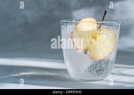 Une vue rapprochée d'un verre d'eau tonique avec une tranche de pomme, soulignant les bulles de la boisson et son aspect rafraîchissant Banque D'Images