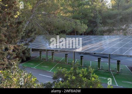 Un parking spacieux équipé de plusieurs auvents de panneaux solaires fournissant de l'énergie à une rangée de bornes de recharge de véhicules électriques Banque D'Images