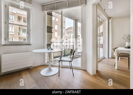 Salle à manger de l'appartement moderne et lumineux avec de grandes fenêtres et un accès au balcon, présentant un design minimaliste. Banque D'Images