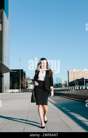 Une femme d'affaires professionnelle avance dans le cadre urbain de Madrid, son expression d'une confiance déterminée. Banque D'Images