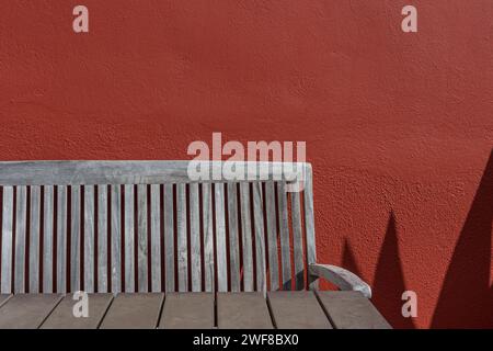 Table et chaise en bois contre mur texturé rouge, Curaçao Banque D'Images