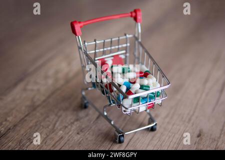 Un panier débordant de pilules colorées sur une table en bois. Copier l'espace pour le texte. Pharmacie en ligne, concept de coûts de santé. Banque D'Images