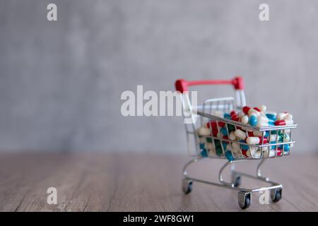 Un panier débordant de pilules colorées sur une table en bois. Copier l'espace pour le texte. Pharmacie en ligne, concept de coûts de santé. Banque D'Images