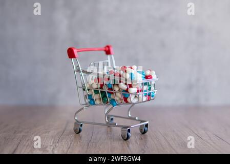 Un panier débordant de pilules colorées sur une table en bois. Copier l'espace pour le texte. Pharmacie en ligne, concept de coûts de santé. Banque D'Images