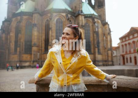 Jeune femme souriante en chemisier jaune et imperméable à Prague République tchèque visite. Banque D'Images