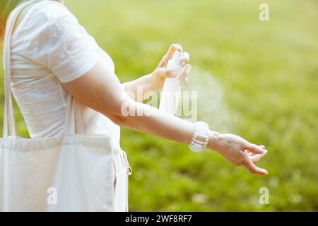 Heure d'été. Gros plan sur femme en chemise blanche en utilisant de la crème solaire dans la prairie à l'extérieur dans la nature. Banque D'Images