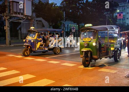 BANGKOK, THAÏLANDE, octobre 28 2023, taxi tricycle traditionnel se trouve devant un passage piéton zèbre dans la ville du soir Banque D'Images