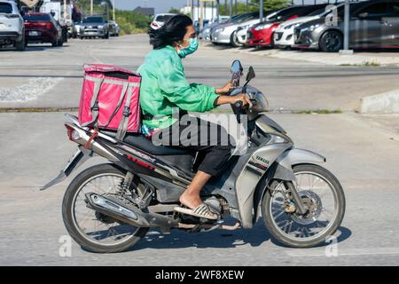 BANGKOK, THAÏLANDE, décembre 05 2023, Un homme conduit une moto avec une boîte de rangement dans la rue Banque D'Images