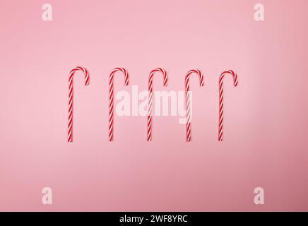 Composition de Noël, bonbons rouges et blancs, cannes de bonbons sur fond rose. Noël, nouvel an, concept d'hiver. Vue de dessus, pose à plat, espace de copie. Banque D'Images
