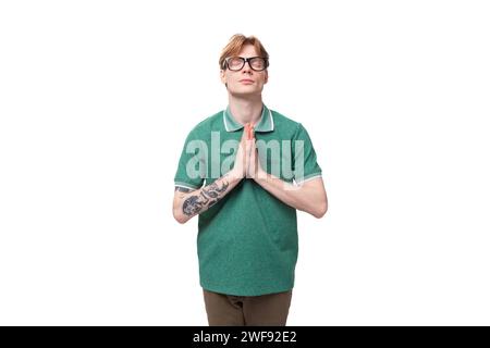 jeune étudiant caucasien aux cheveux roux et tatoué a mis ses mains ensemble dans l'anticipation et l'espoir Banque D'Images