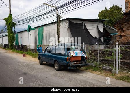Une petite camionnette bleue est garée sur le côté d'une route urbaine très fréquentée, entourée de bâtiments et de circulation. Banque D'Images