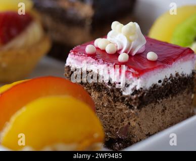 Une variété de desserts délicieux magnifiquement disposés sur un plat blanc immaculé, accompagnés d'un fruit vibrant et succulent Banque D'Images