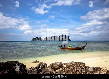 Un petit bateau est stationné sur une plage de sable avec en toile de fond des formations rocheuses. Banque D'Images