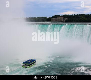 Chutes du Niagara, Onterio, Canada - 30 juillet 2023 : bateau d'excursion aux chutes du Niagara avec des touristes en imperméables bleus s'approchant de la brume des chutes du fer à cheval. Banque D'Images