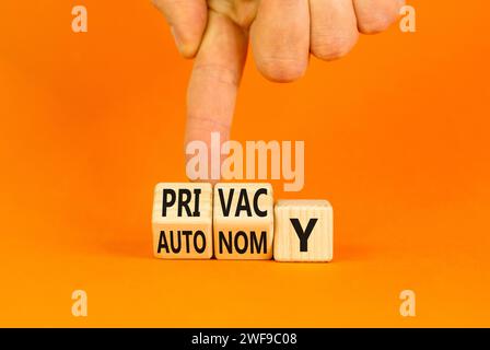 Symbole de confidentialité ou d'autonomie. Mot concept vie privée ou autonomie sur cubes en bois. Belle table orange fond orange. Main d'homme d'affaires. pri entreprise Banque D'Images