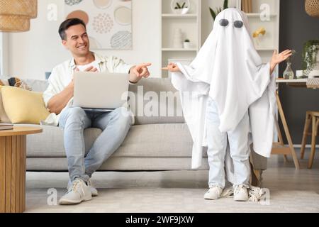 Drôle petite fille en costume fantôme avec son père à la maison Banque D'Images