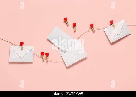 Enveloppes avec carte vierge accrochant sur la corde sur fond de couleur. Fête de la Saint-Valentin Banque D'Images