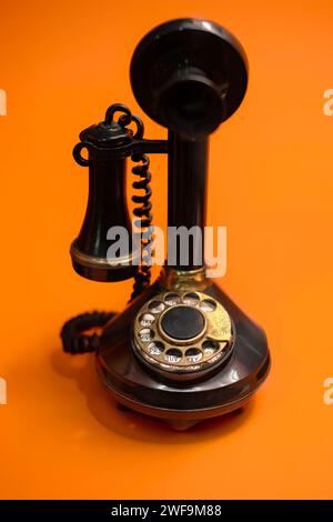 Téléphone à cadran rotatif vintage sur un fond orange vif Banque D'Images