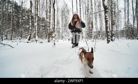 Une fille et son chien Jack Russell Terrier courent dans les bois. Banque D'Images