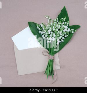 Carte de voeux élégante avec un bouquet de lys blancs de la vallée dans une enveloppe Banque D'Images