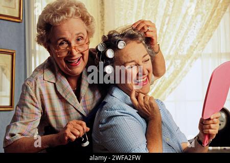 Un portrait de deux femmes âgées meilleures amies posant joyeusement ensemble, souriant et tenant un miroir dans leurs mains. Banque D'Images